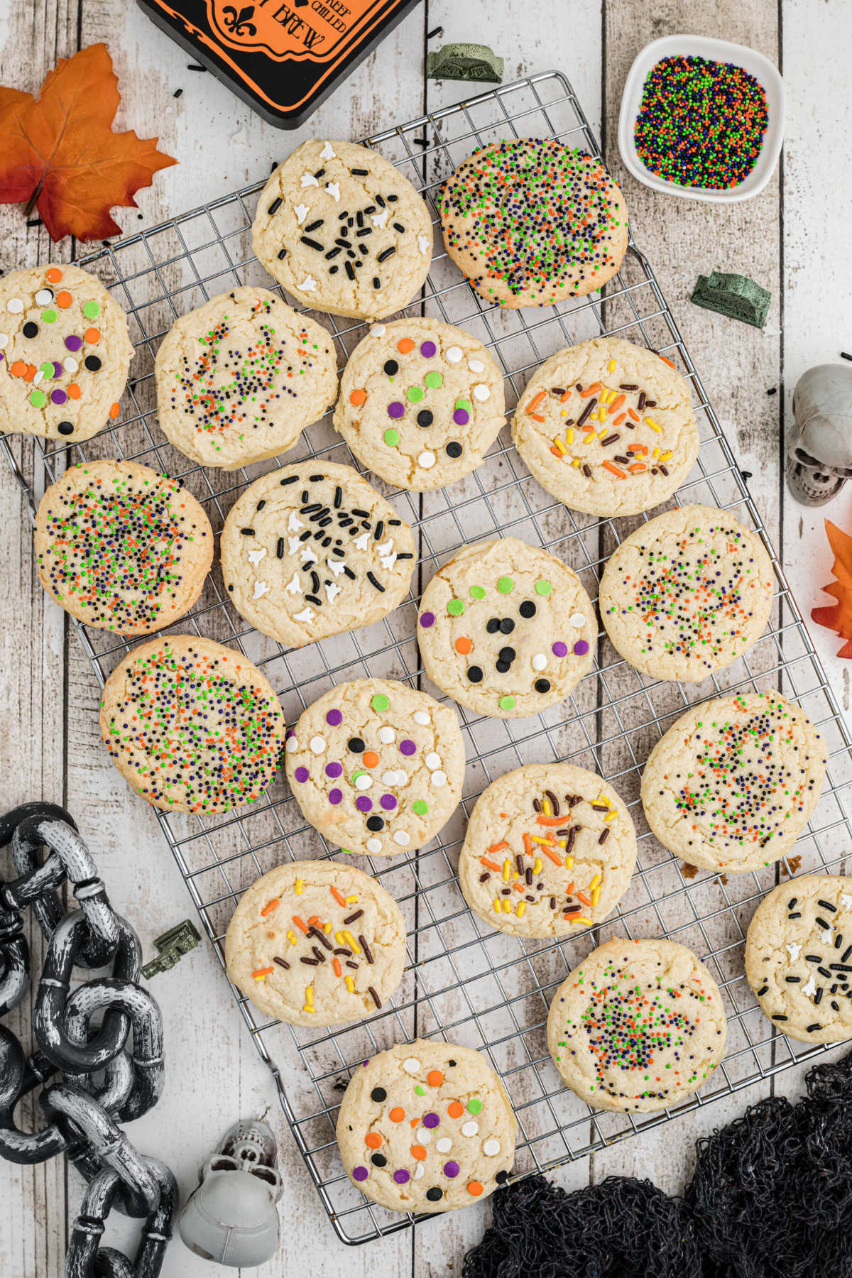 Wire rack with cookies decorated with sprinkles in halloween colors.