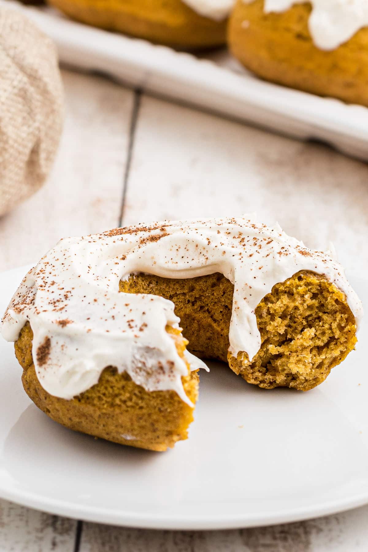 close up of a pumpkin spice donut with a bit taken out of it.