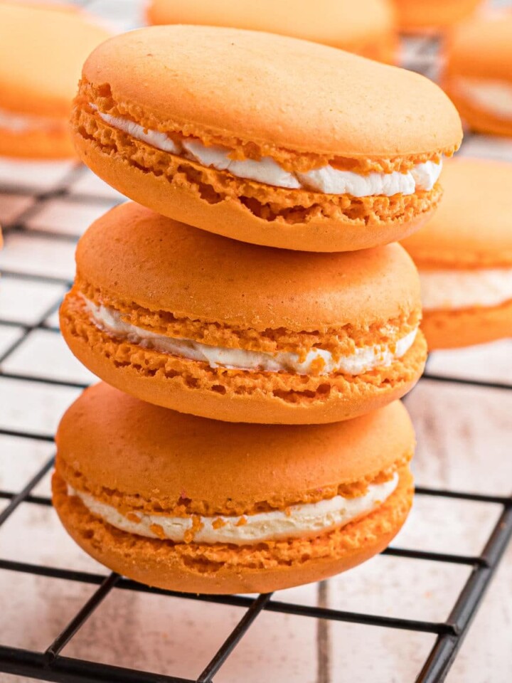 A close up shot of a stack of three pumpkin spice macarons.