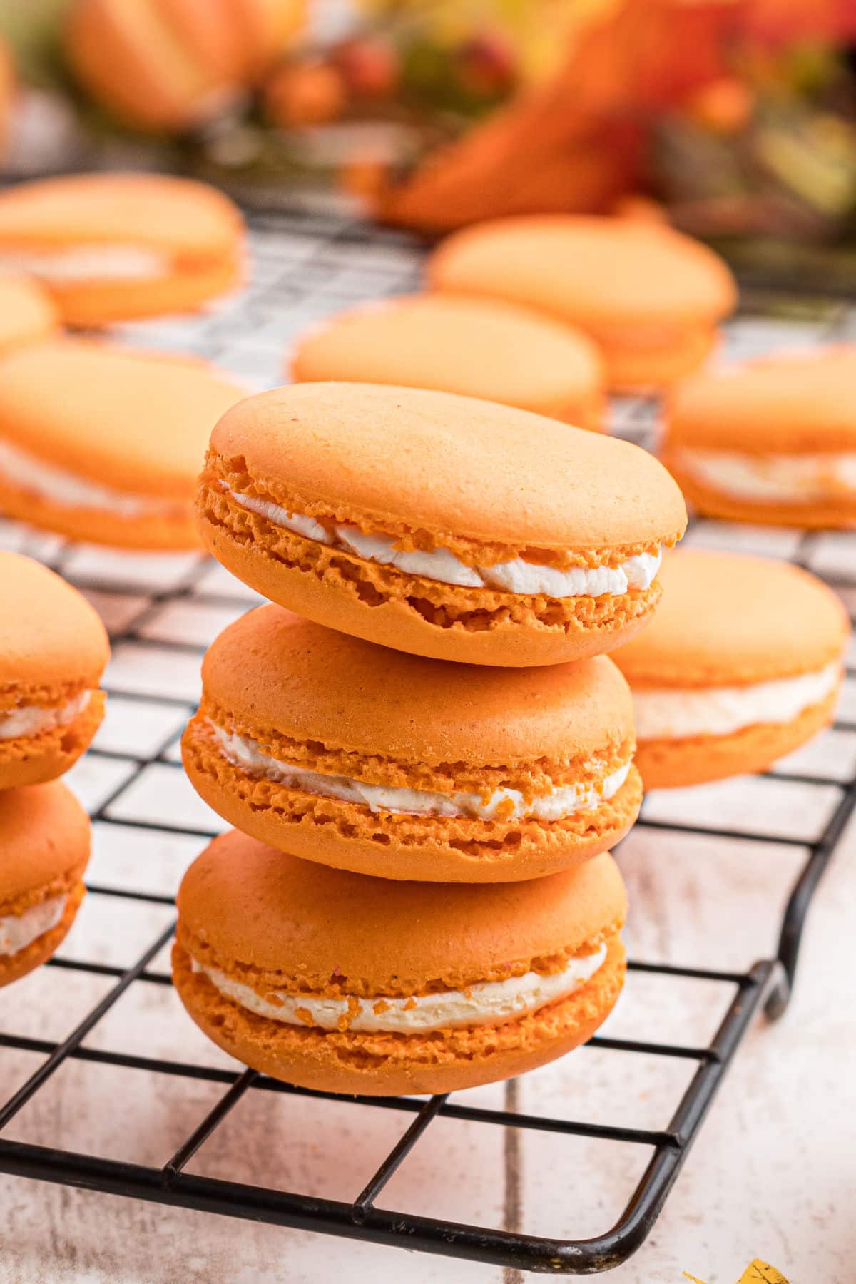 A close up of 3 pumpkin spice macarons in a stack.