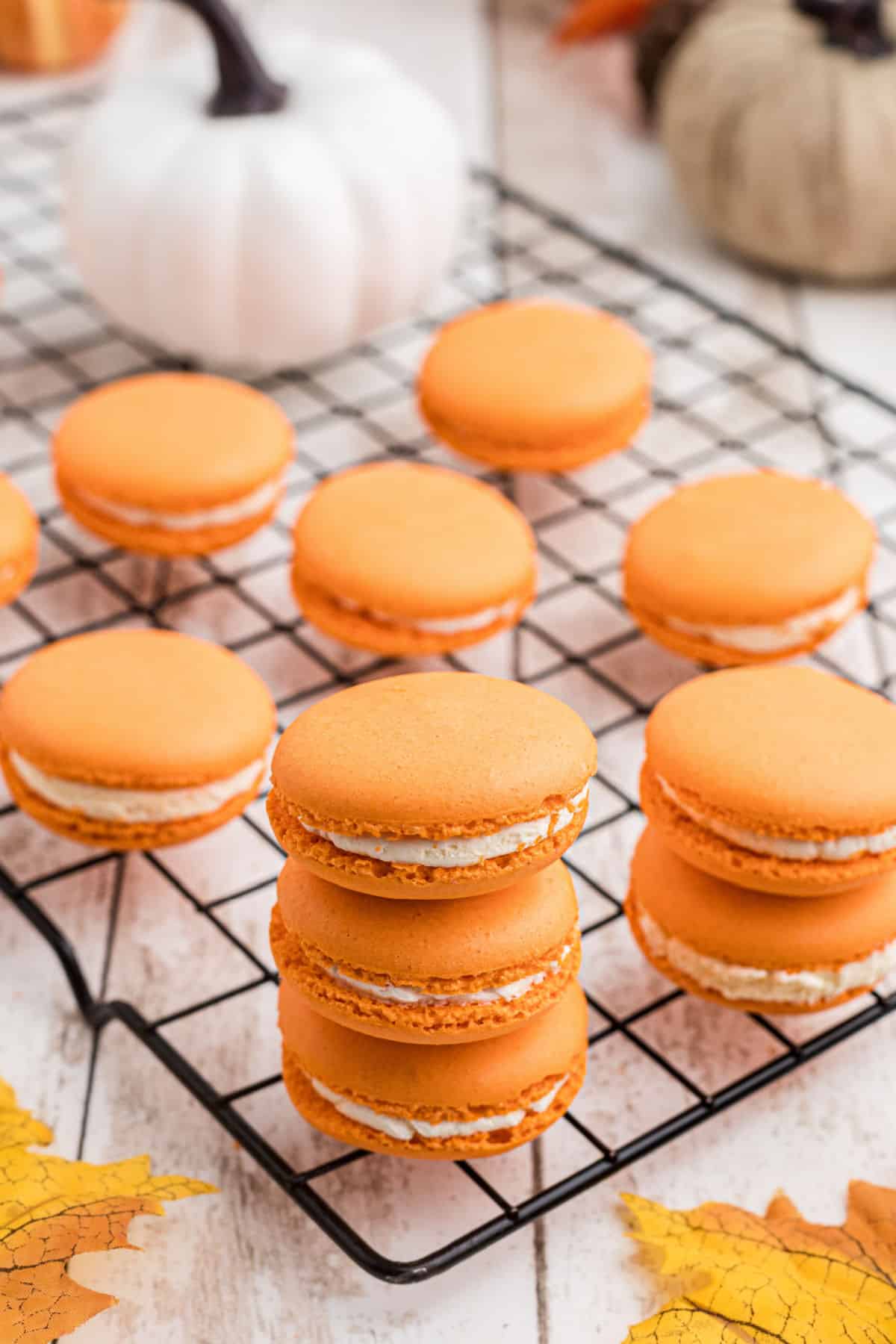 Wire rack with pumpkin spice macarons piled.