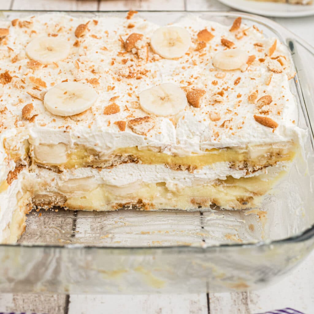 A dish full of no bake banana pudding with a few pieces missing.