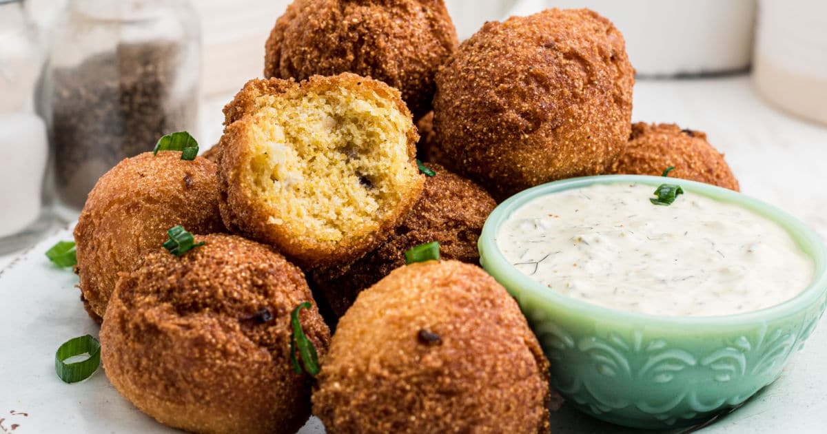 close up of some hush puppies next to some dip.