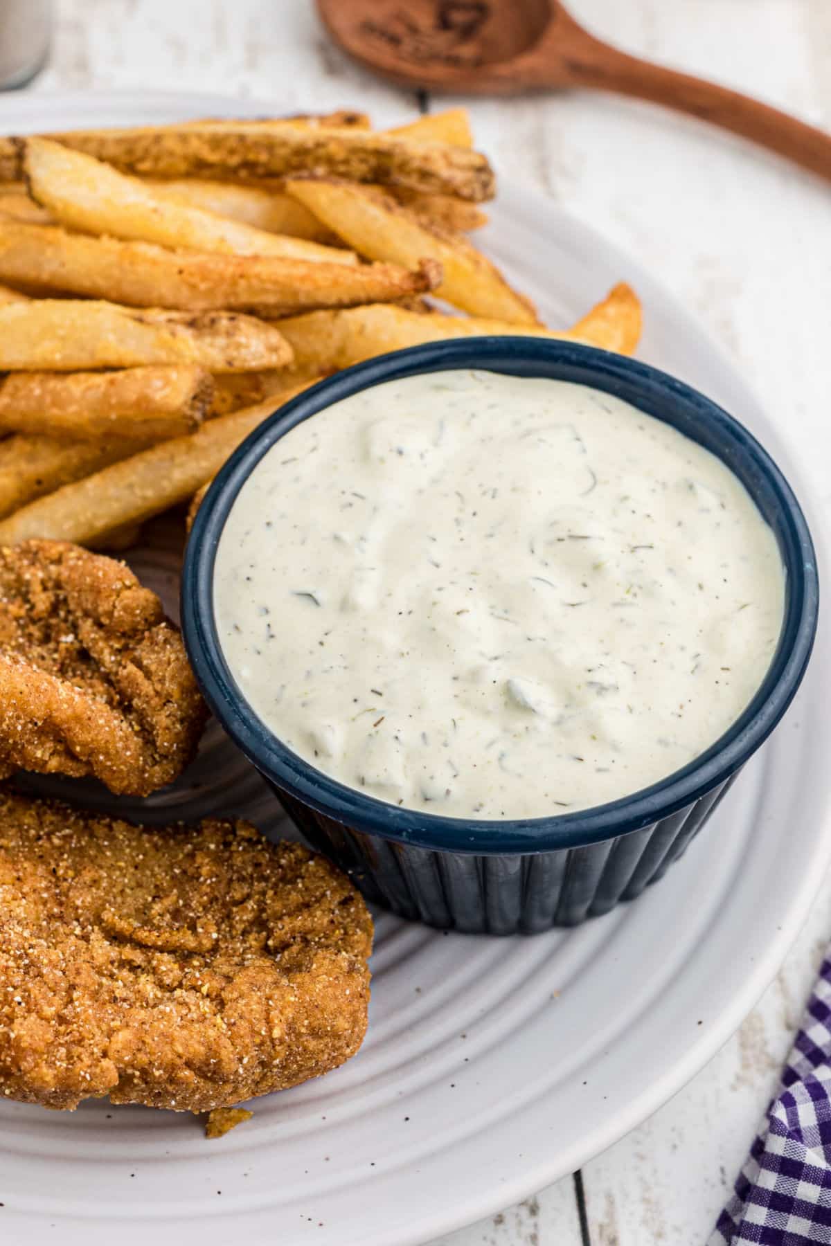 an overhead view of a dish of tartar sauce with some fish on the side.