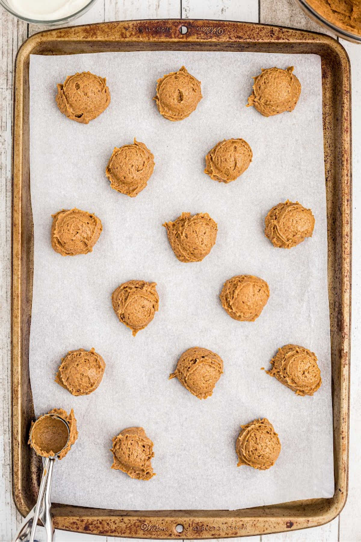 Pumpkin spice cookies being spooned onto a baking sheet.
