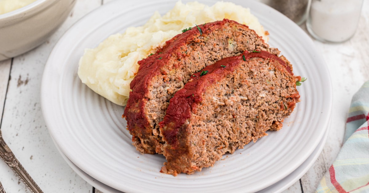 two slices of venison meatloaf resting against some mashed potatoes.