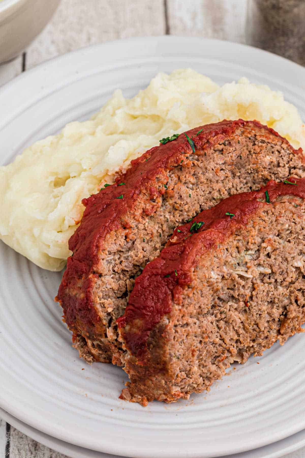 Two slices of meatloaf against some mashed potatoes.