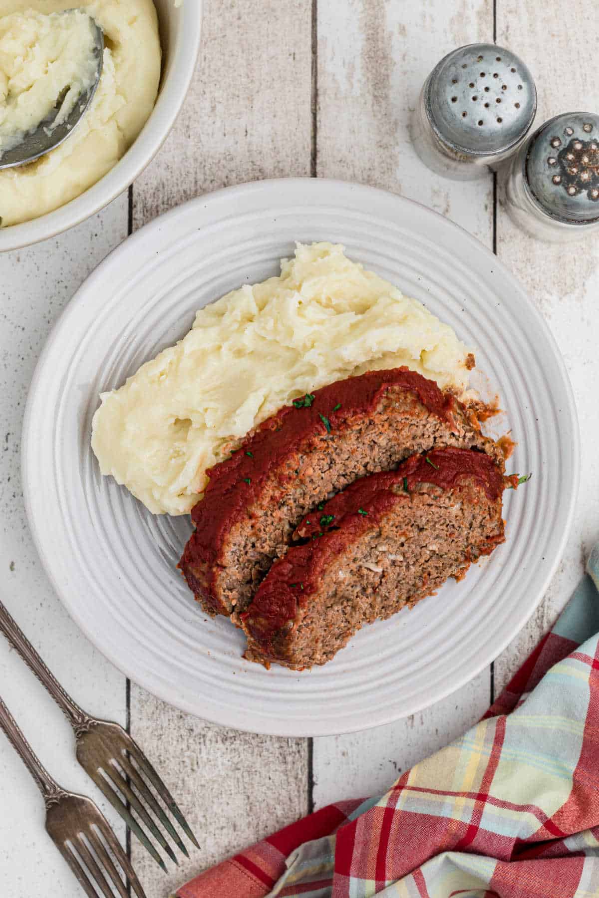 Overhead shot of a plate of mashed potatoes with meatloaf.