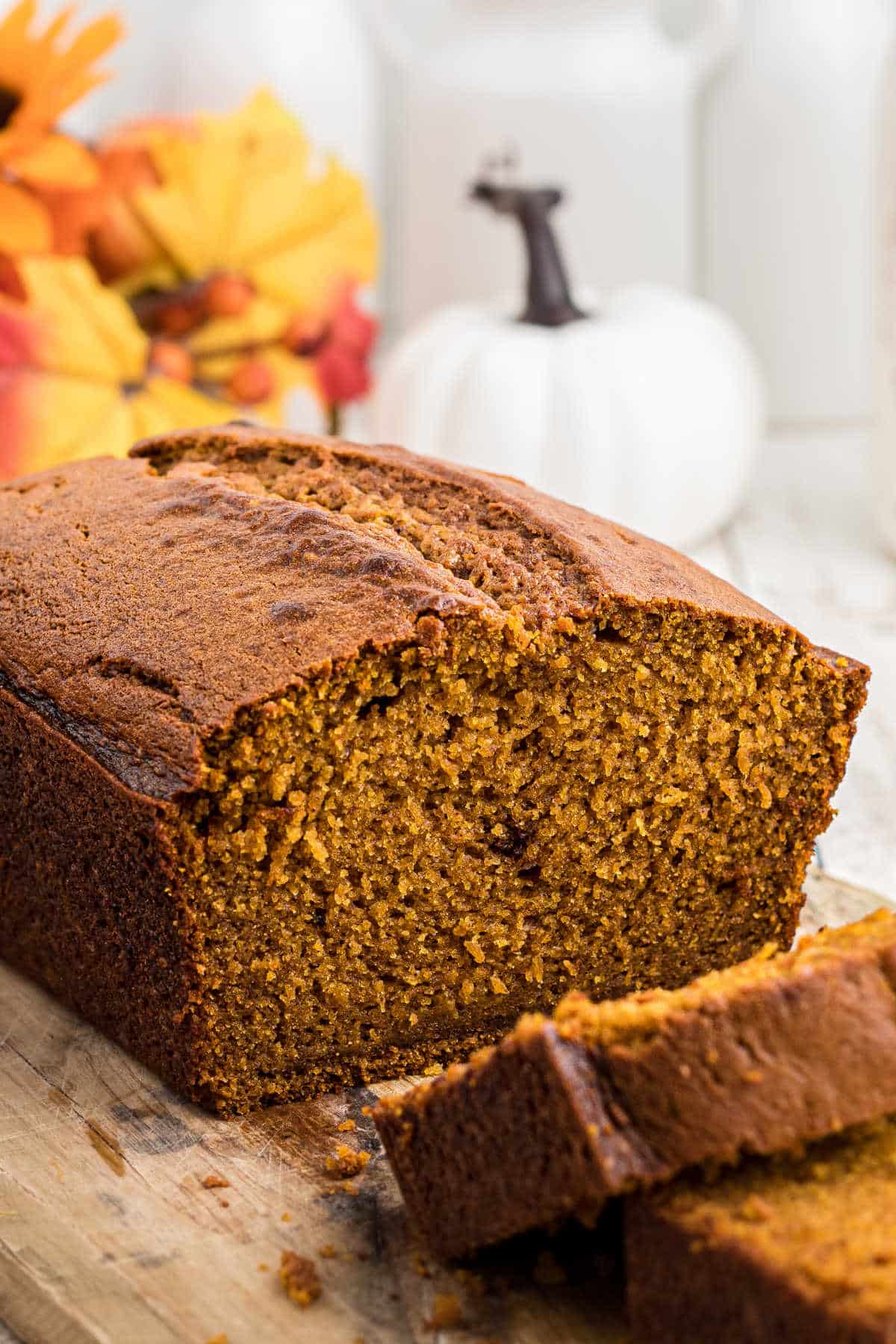 Close up side view of an Amish Pumpkin Bread with two slices laying in front of it.