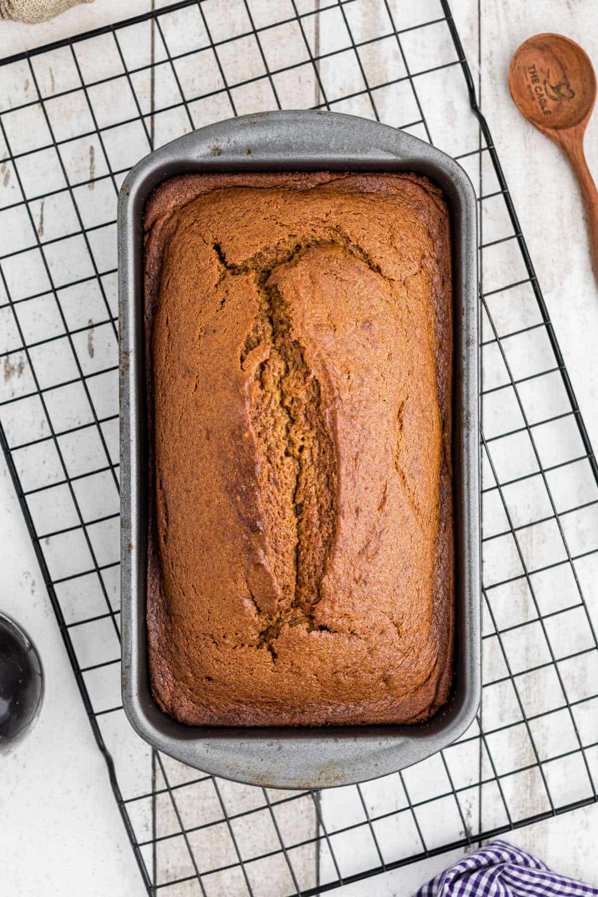 A cooked Amish Pumpkin Bread still in the pan on a cooling wire rack.