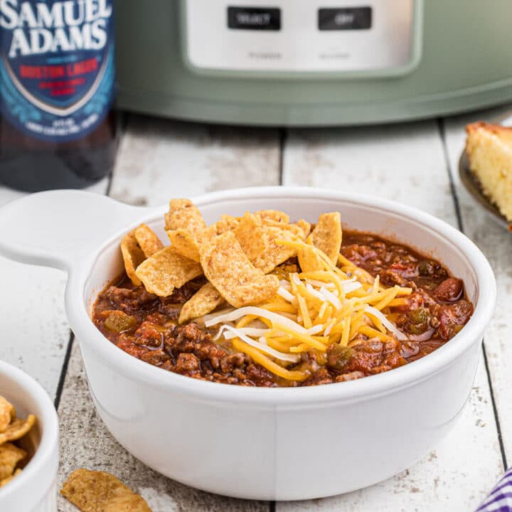 Close up side view of a bowl of beer chili with a crock pot in the background.