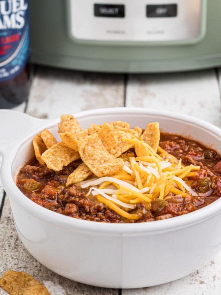 Close up side view of a bowl of beer chili with a crock pot in the background.