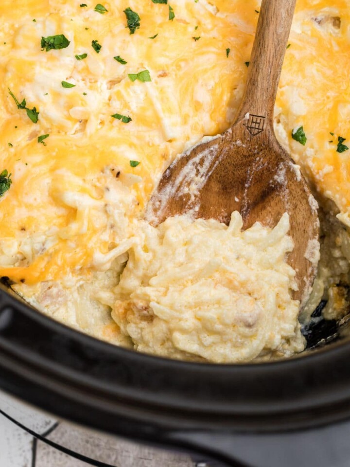 close up of a spoon digging into a hash brown casserole.