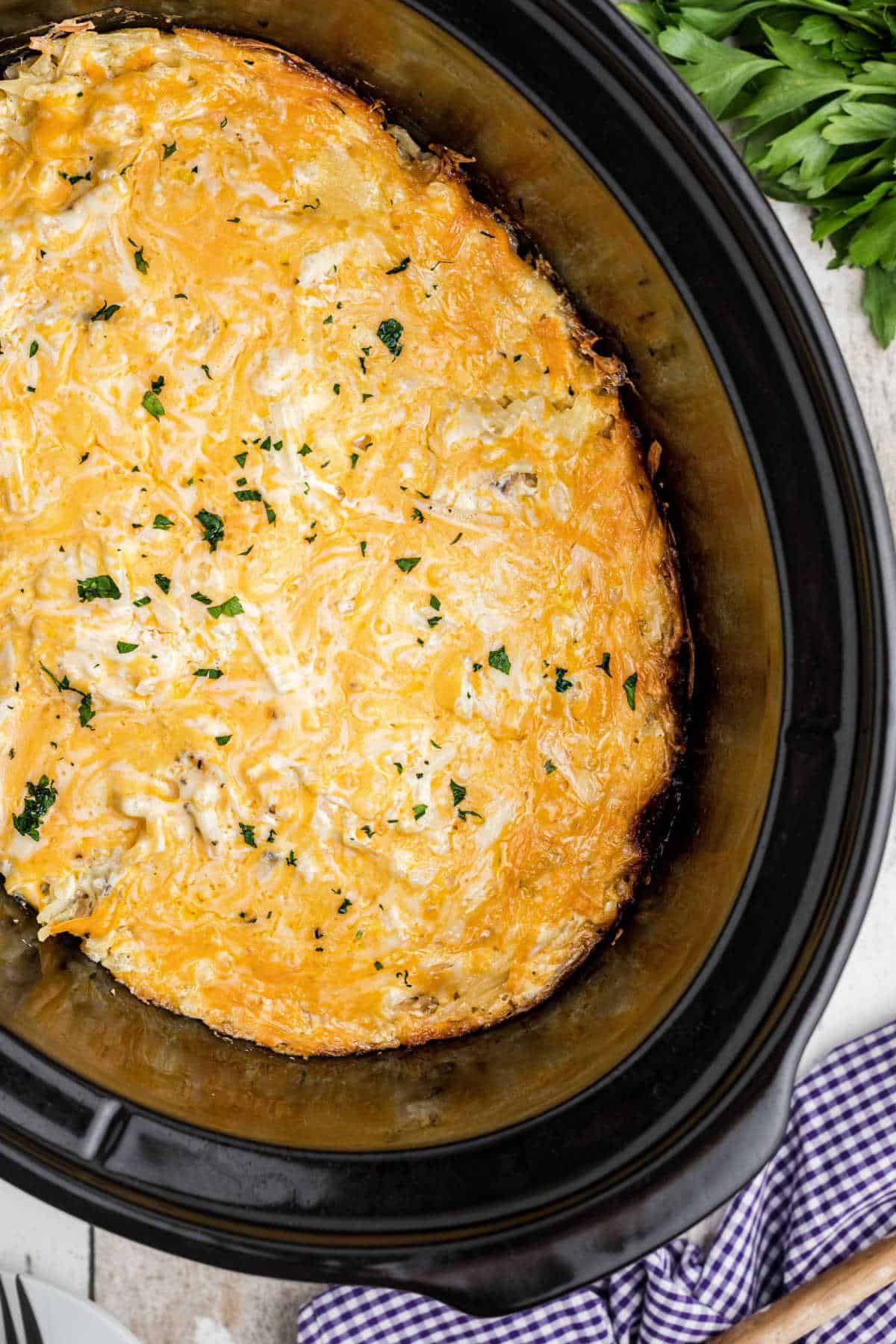 Overhead shot of a slow cooker with a hash brown casserole inside, looks cheesy.