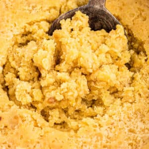 A close up of a corn casserole disturbed by a spoon.