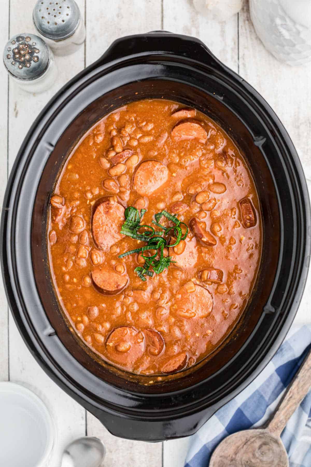 Overhead shot of a slow cooker filled with kielbasa and baked beans.