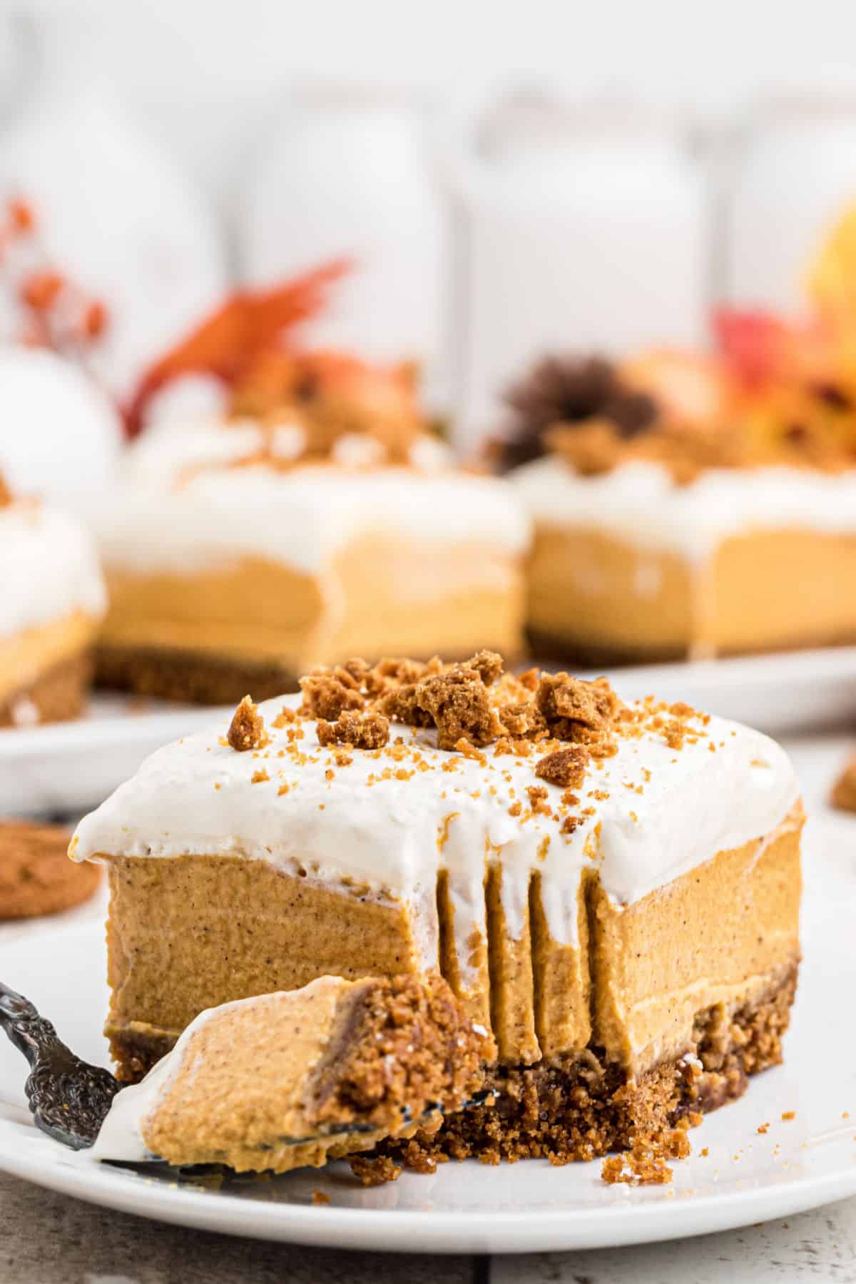 Close up of a slice of no bake pumpkin cheesecake bars with a fork print in the front corner.