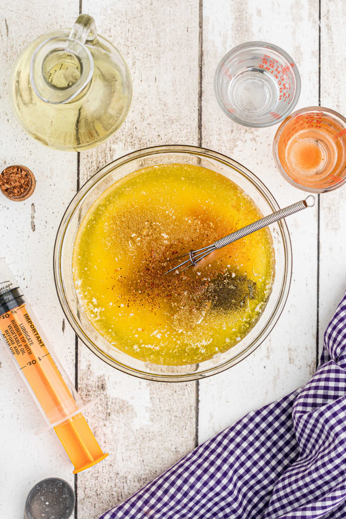 A small mixing bowl with melted butter, olive oil, hot sauce and other seasonings.