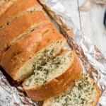 A sliced garlic bread stuffed with cheese with text overlay for pinterest.