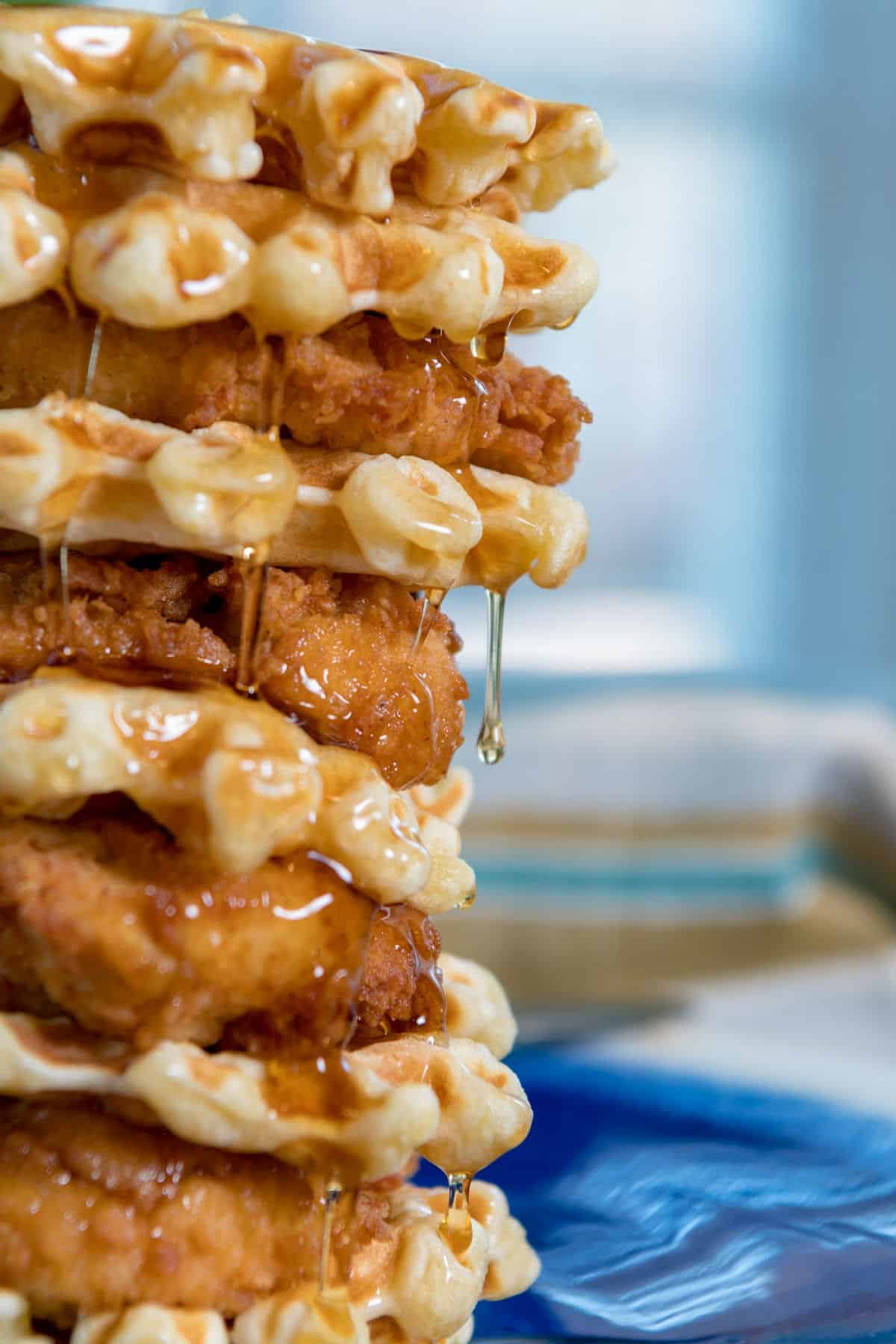 A stack of fried chicken and waffles with syrup dripping off the edges.