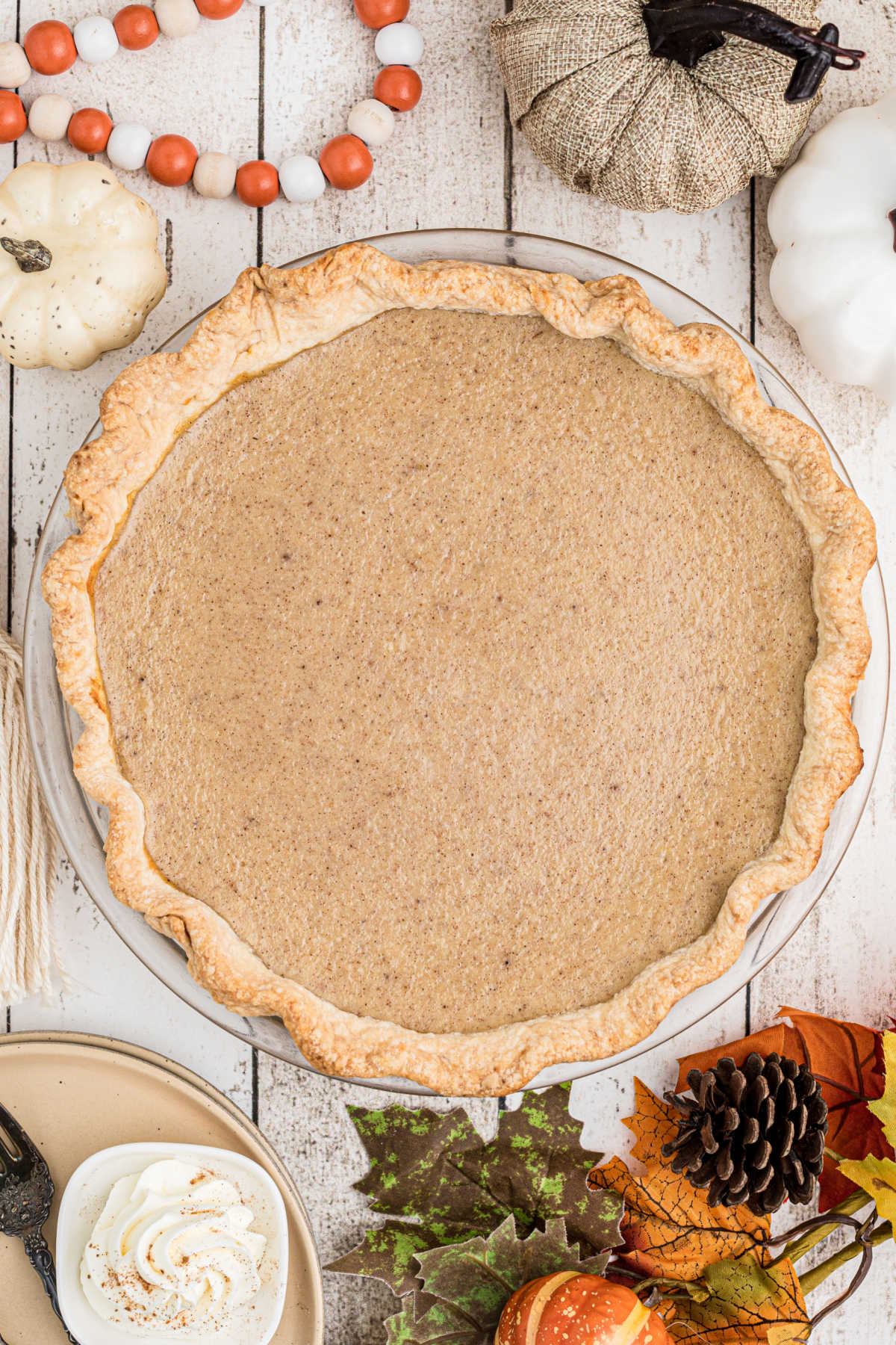 An overhead view of a white pumpkin pie with fall decorations all around.