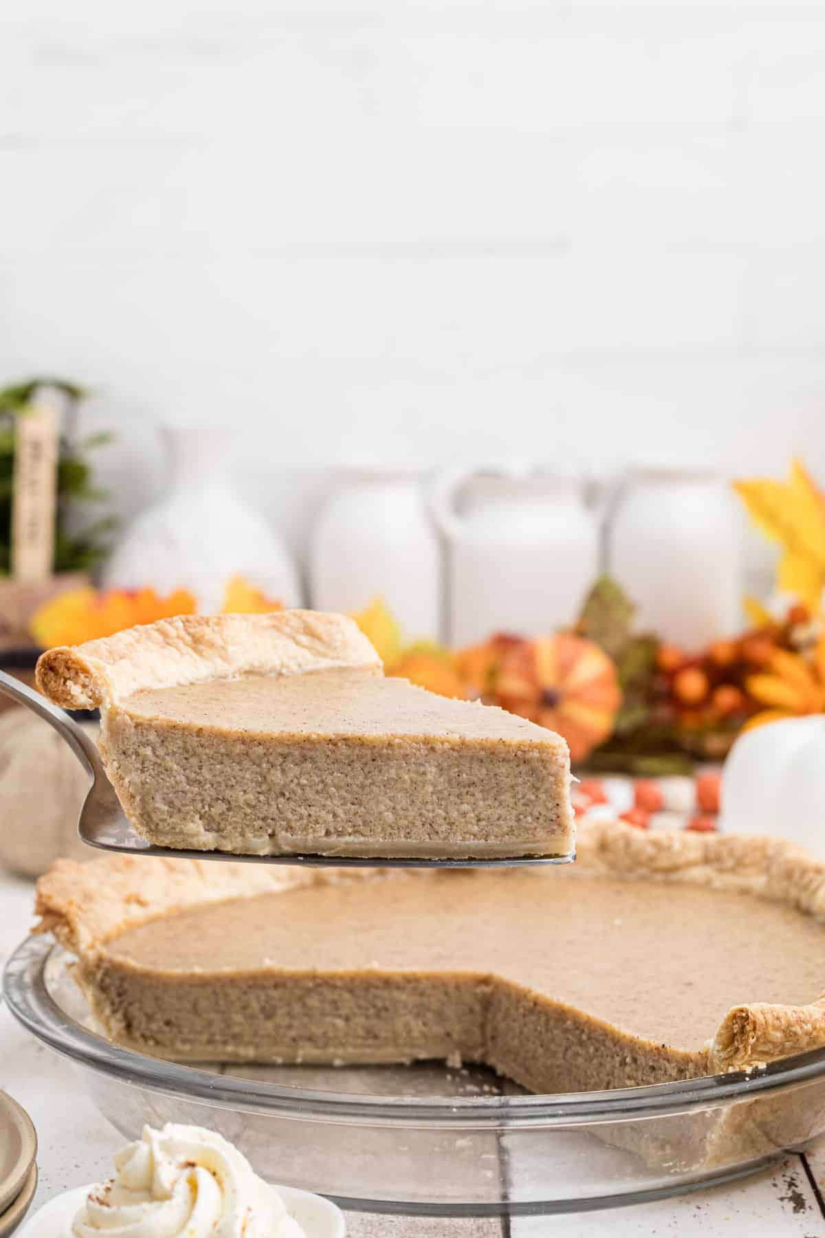 A slice of white pumpkin pie being pulled out of a pie dish.