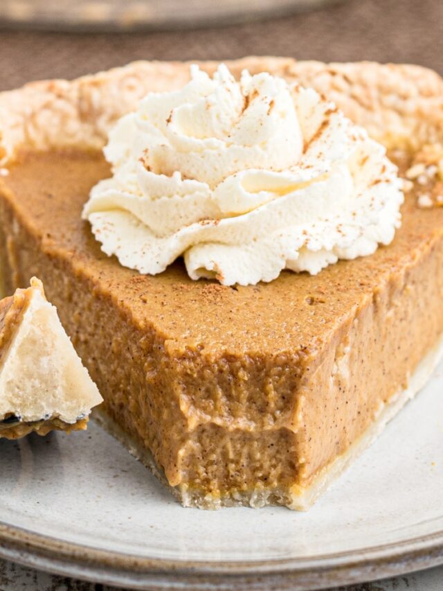 A close up of a slice of pumpkin pie with a fork having taken a piece from the front.