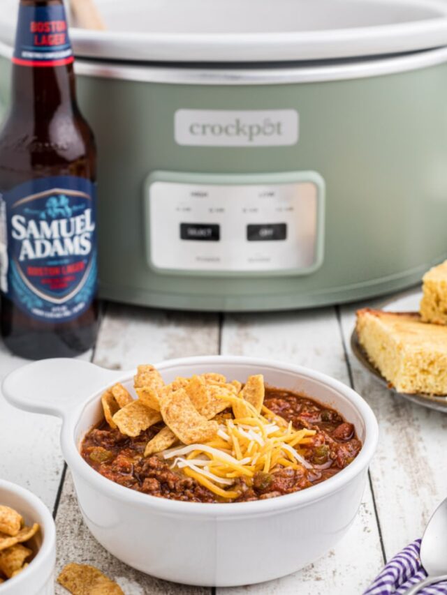 a bowl of beer chili in front of a crock pot with a bottle of beer.