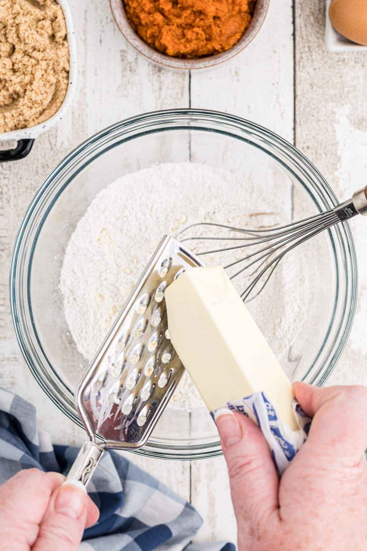 Butter being grated into a bowl of flour to make a pie crust.