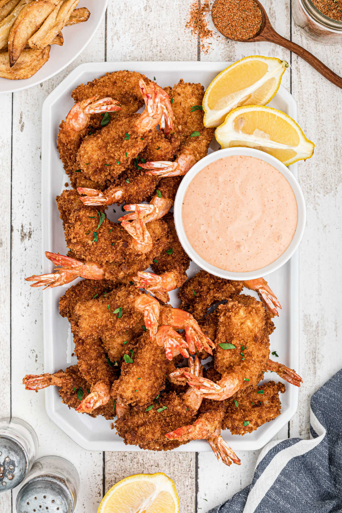 A plate of butterfly shrimp with some dip and lemon.