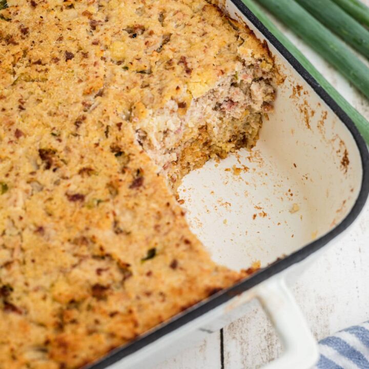 A corner of a dish with Cajun cornbread dressing made in it, with a corner scooped out.