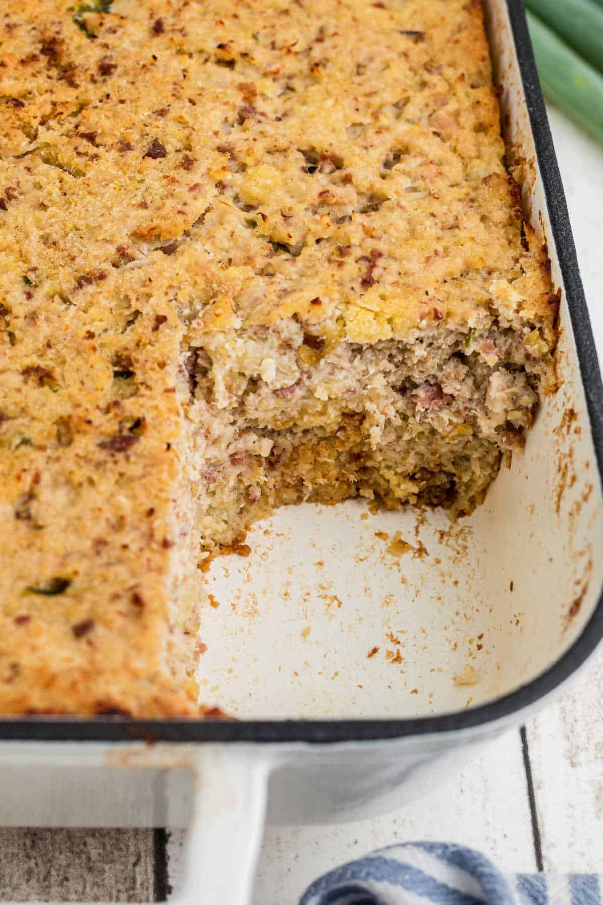 View of the side of a dish with a cornbread dressing in it, with the corner missing.