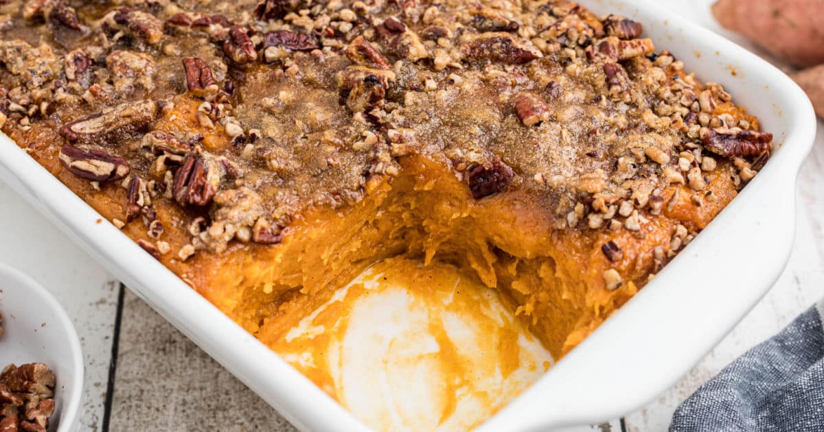 A corner of a dish of sweet potato casserole with a scoop missing.