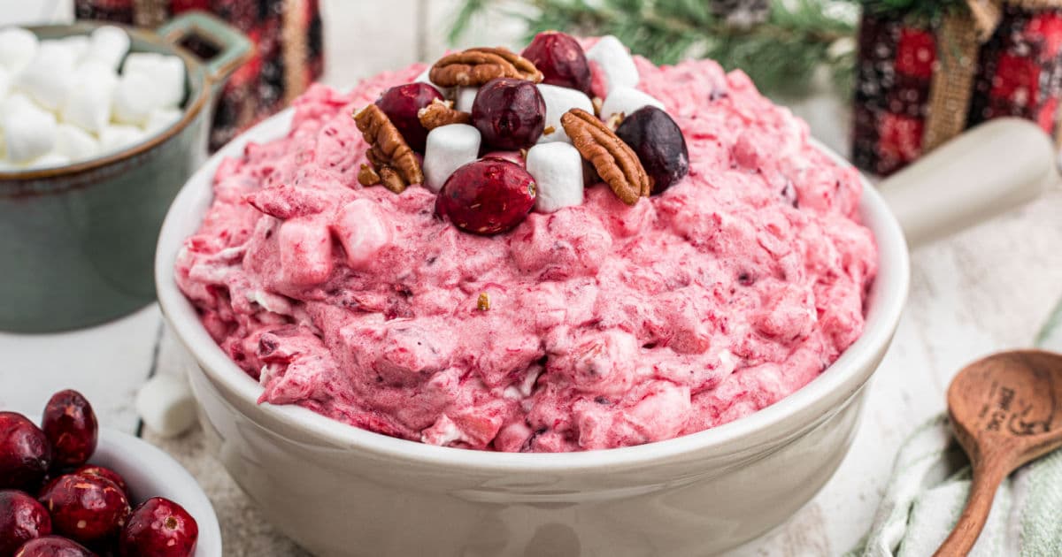 A dish of cranberry salad with some marshmallows and pecans sprinkled on top.