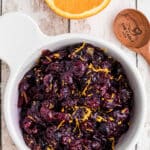 A bowl of dried cranberry sauce with orange zest and some text overlay for Pinterest.