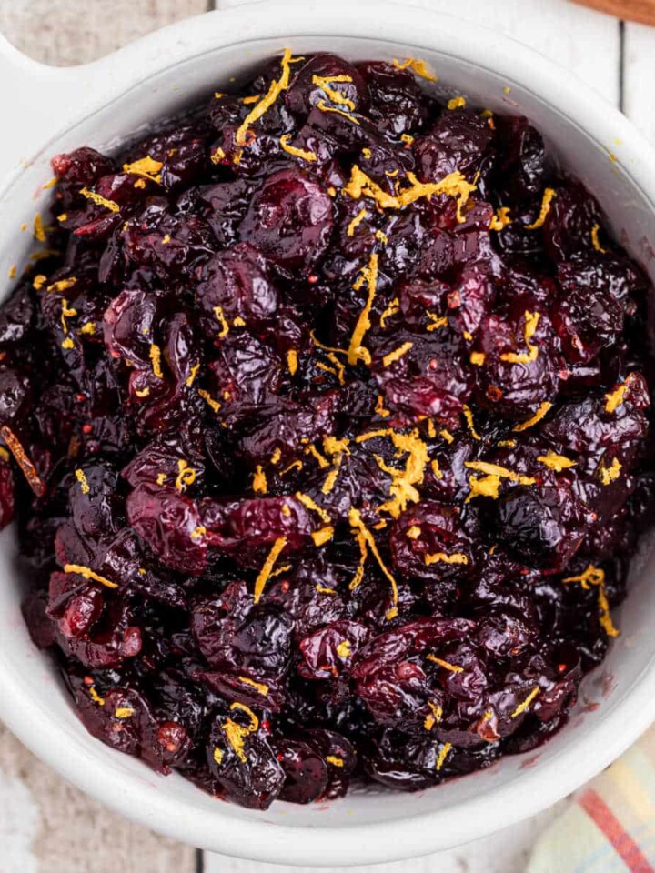 close up overhead image of a bowl of dried cranberry sauce with some orange zest sprinkled on top.
