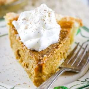 a slice of butternut squash pie with a dollop of cream on top.