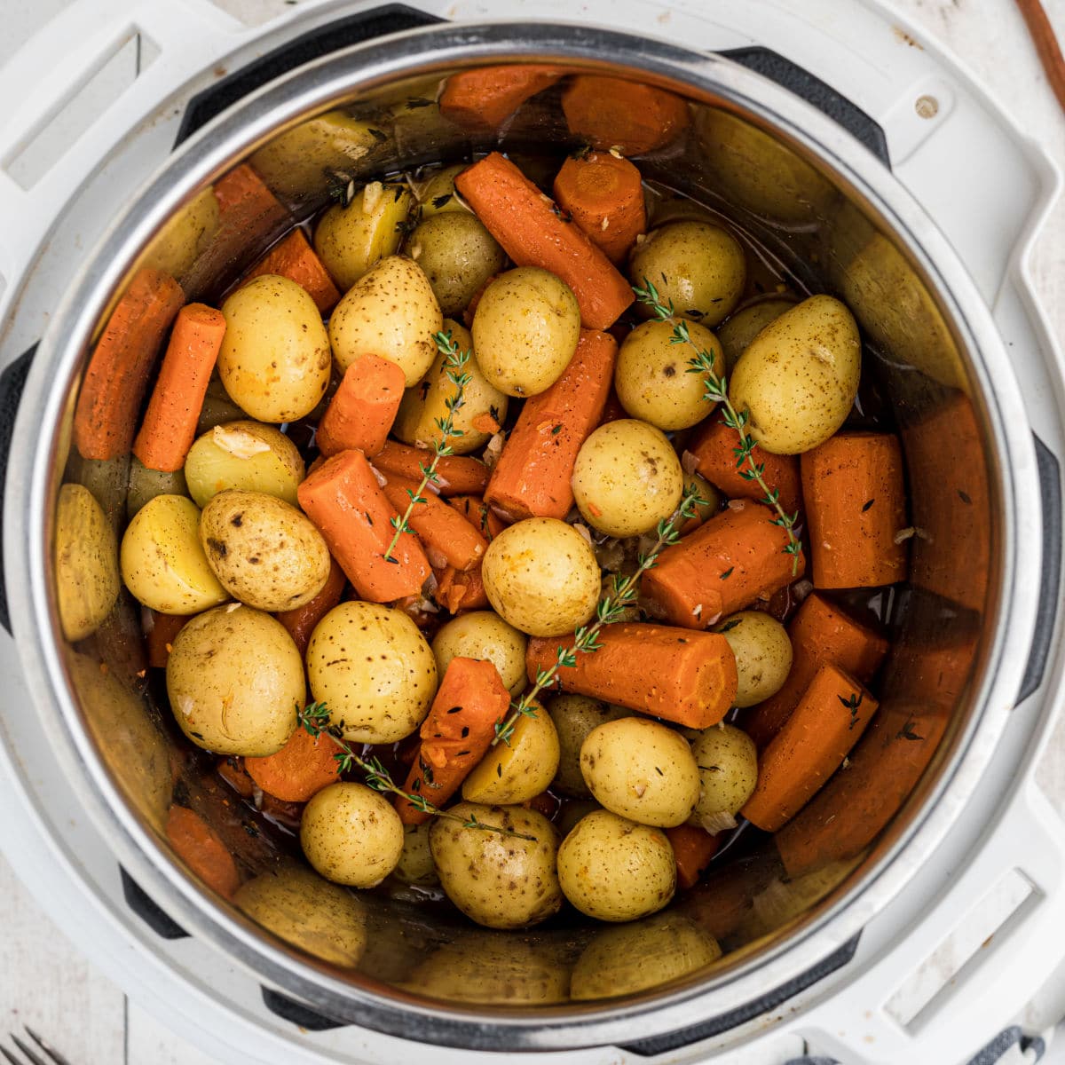 Close up overhead of an instant pot with potatoes and carrots.