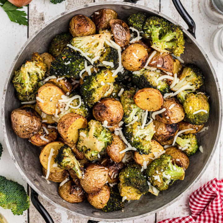 Cropped square image of a pan full of roasted potatoes and broccoli.