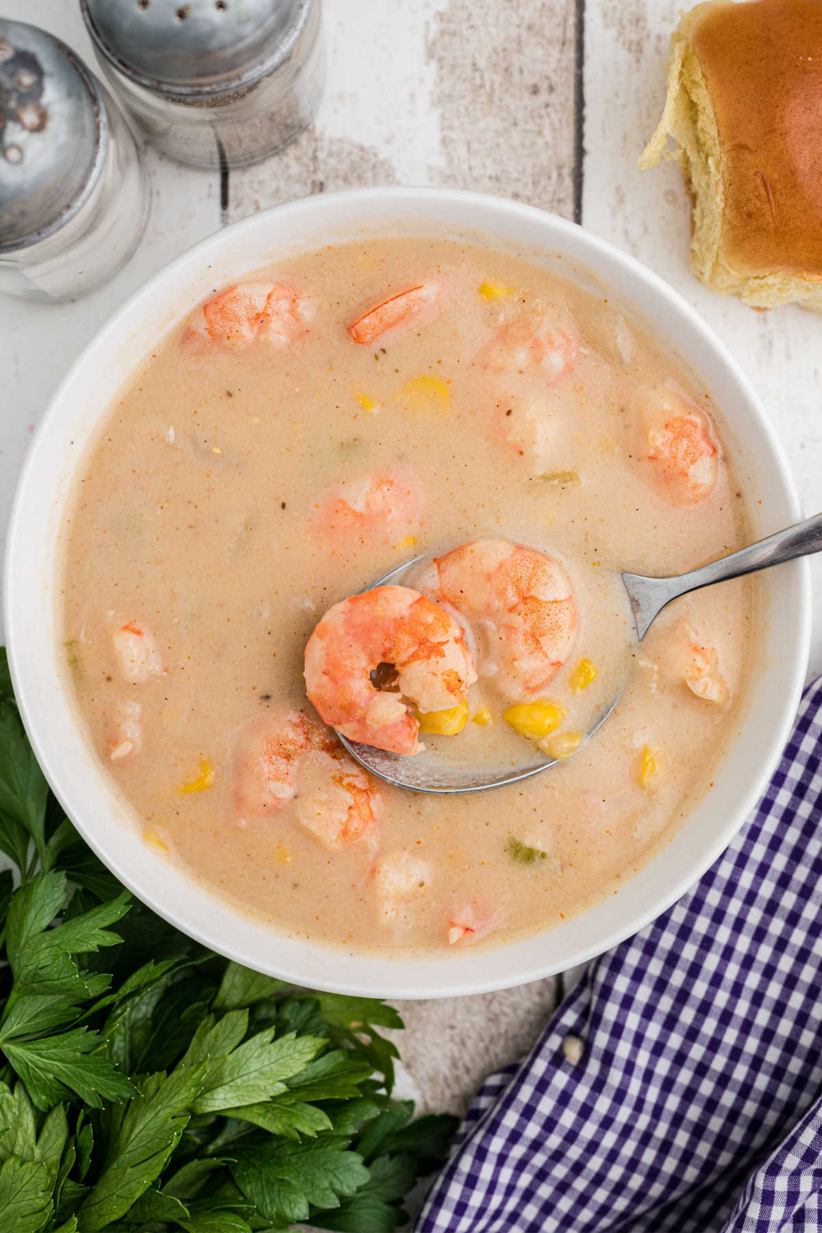overhead shot of a bowl of shrimp and corn bisque with a spoon digging in.