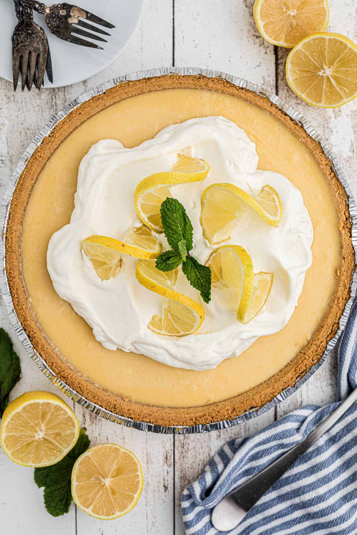 Overhead shot of a southern lemon pie recipe with some cream and lemon slices in the middle and a sprig of mint.