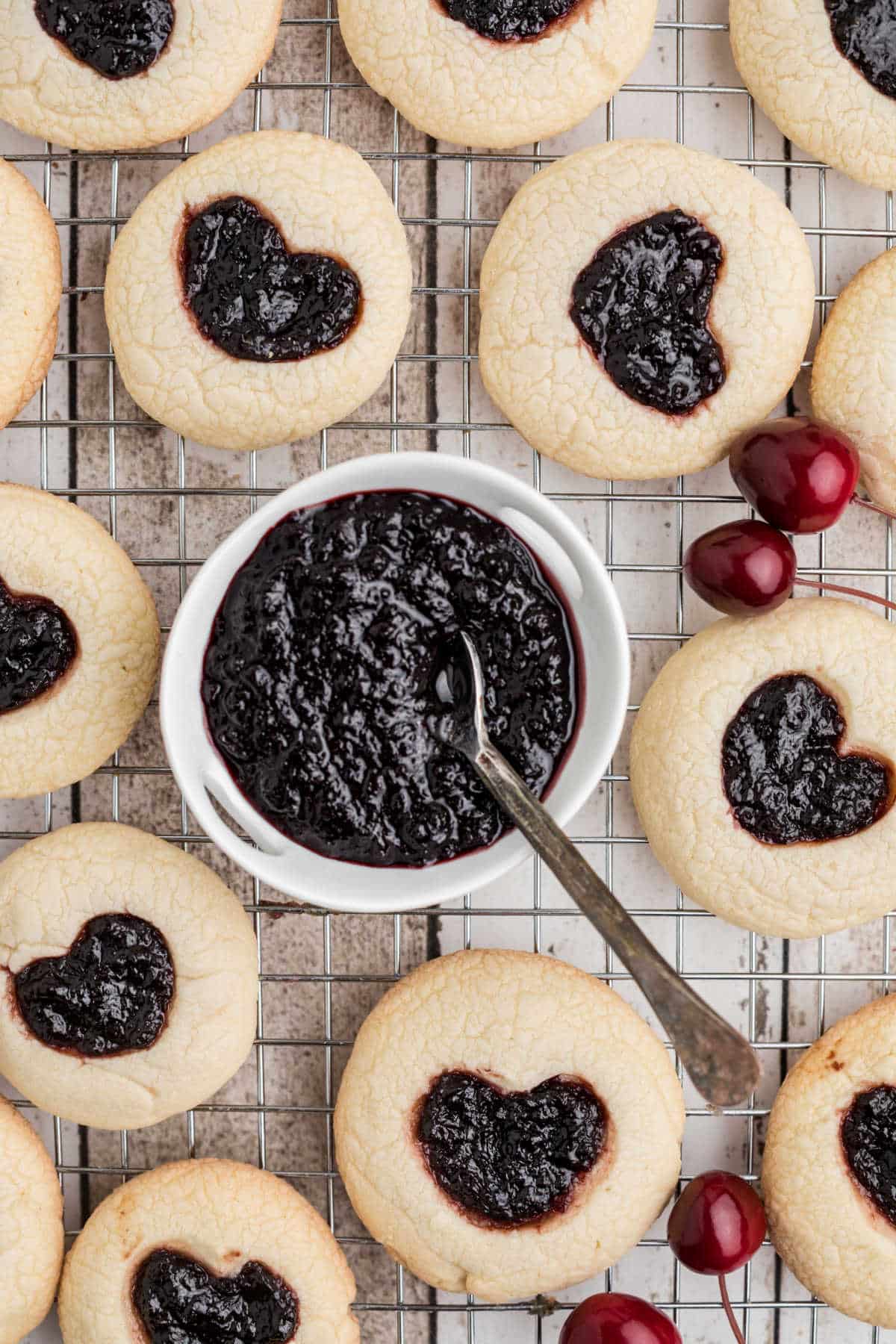 Jam heart cookies surrounding a small bowl filled with Cherry Jam.