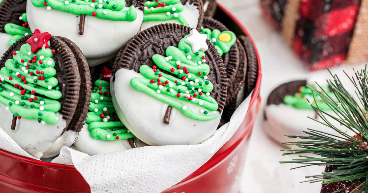 A tin full of Christmas Oreo Cookies with Christmas Trees on them.