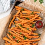 Crispy sweet potatoes all laid out on a baking sheet with text overlay for pinterest.