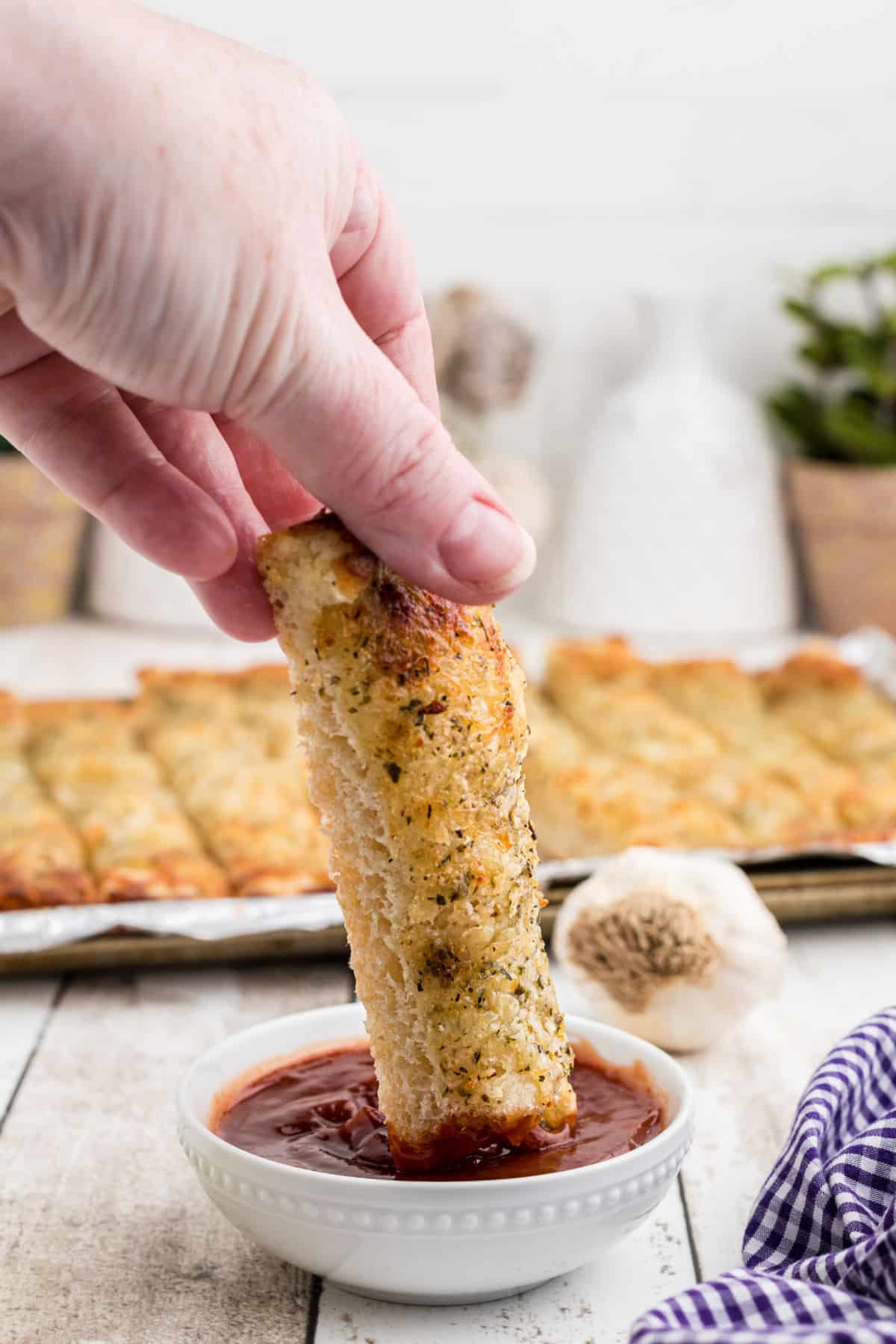 An italian cheese bread stick being dipped into a sauce.