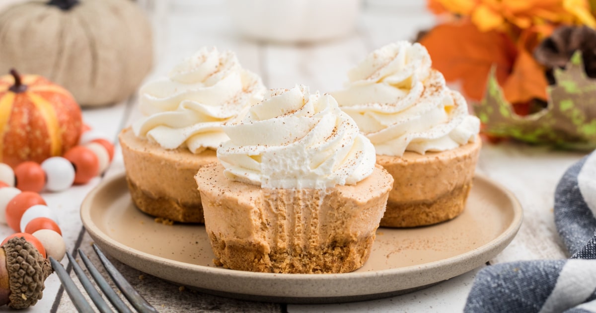 Three no bake mini pumpkin pies on a plate with the front one having a fork mark down the front.