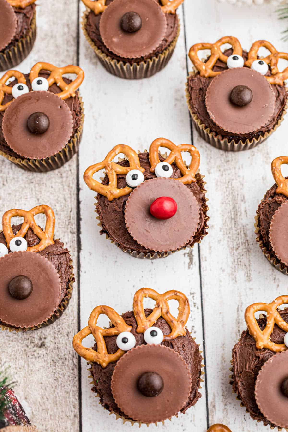 Side view of a lot of reindeer cupcakes with Rudolph in the middle with his red nose.