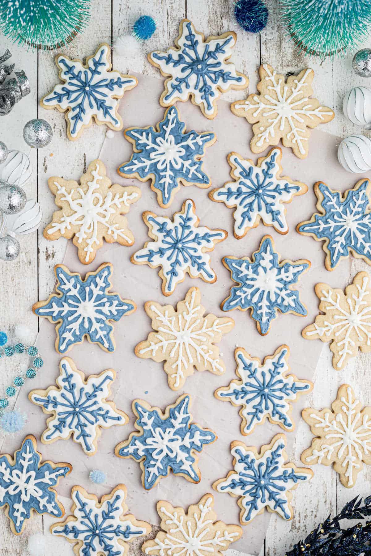 Overhead shot of a lot of snowflake cookies in white and blue.