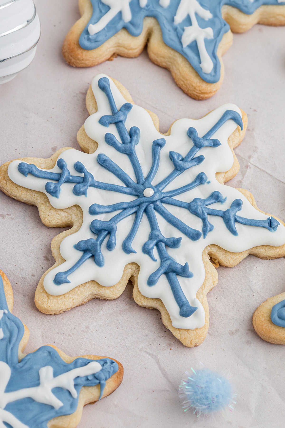 Close up of a snowflake cookie with white and blue icing.