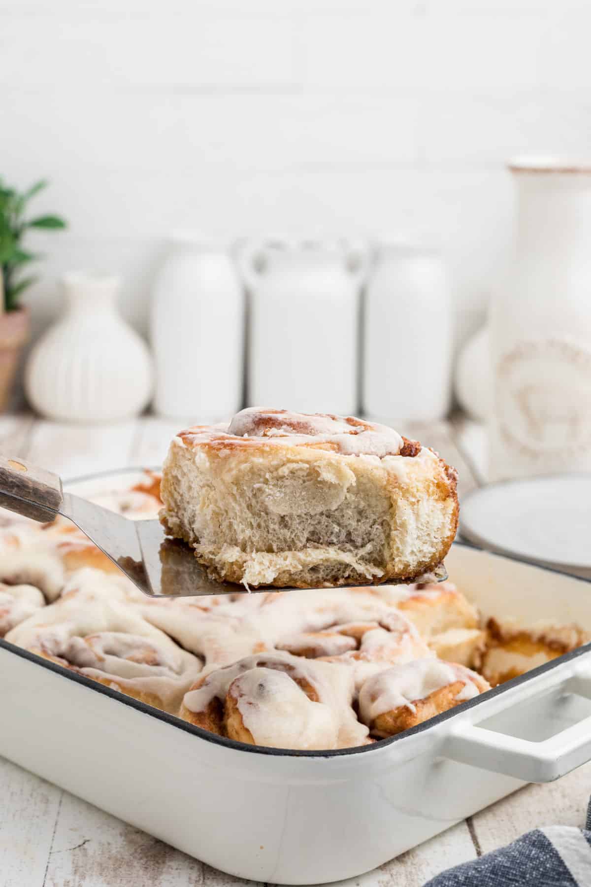 A scoop of an Amish Cinnamon Roll out of a pan.